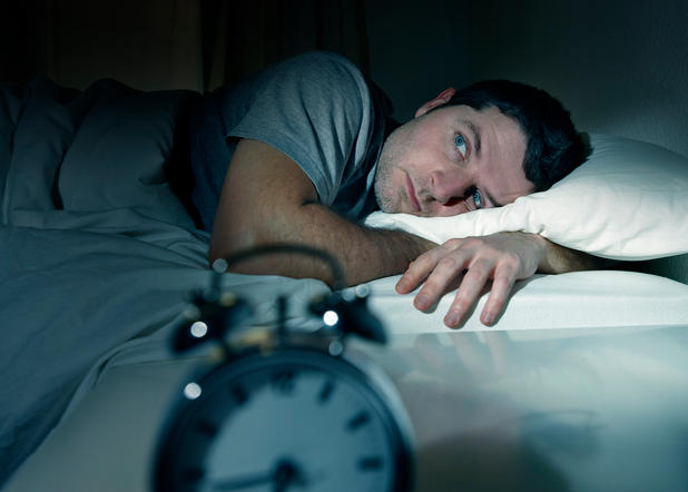 Mann liegt nachts wach im Bett